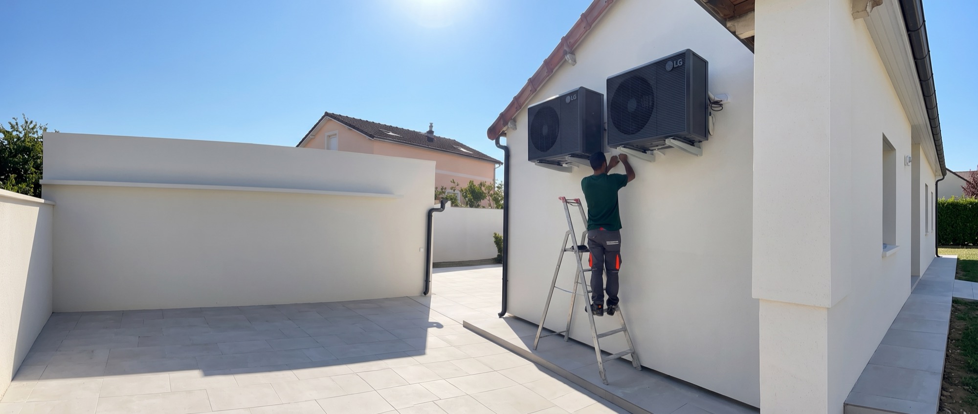 Technicien LATO vu de dos sur une échelle, installant deux unités extérieures LG en façade d'une maison